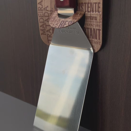 Vídeo de anúncio da espátula para fritura Tramontina, com lâmina de inox e cabo em madeira Polywood vermelho. Ideal para uso em chapas, garantindo praticidade e durabilidade. Perfeita para lanches e preparos rápidos. Encontre a espátula Tramontina na Salvador Comercial.