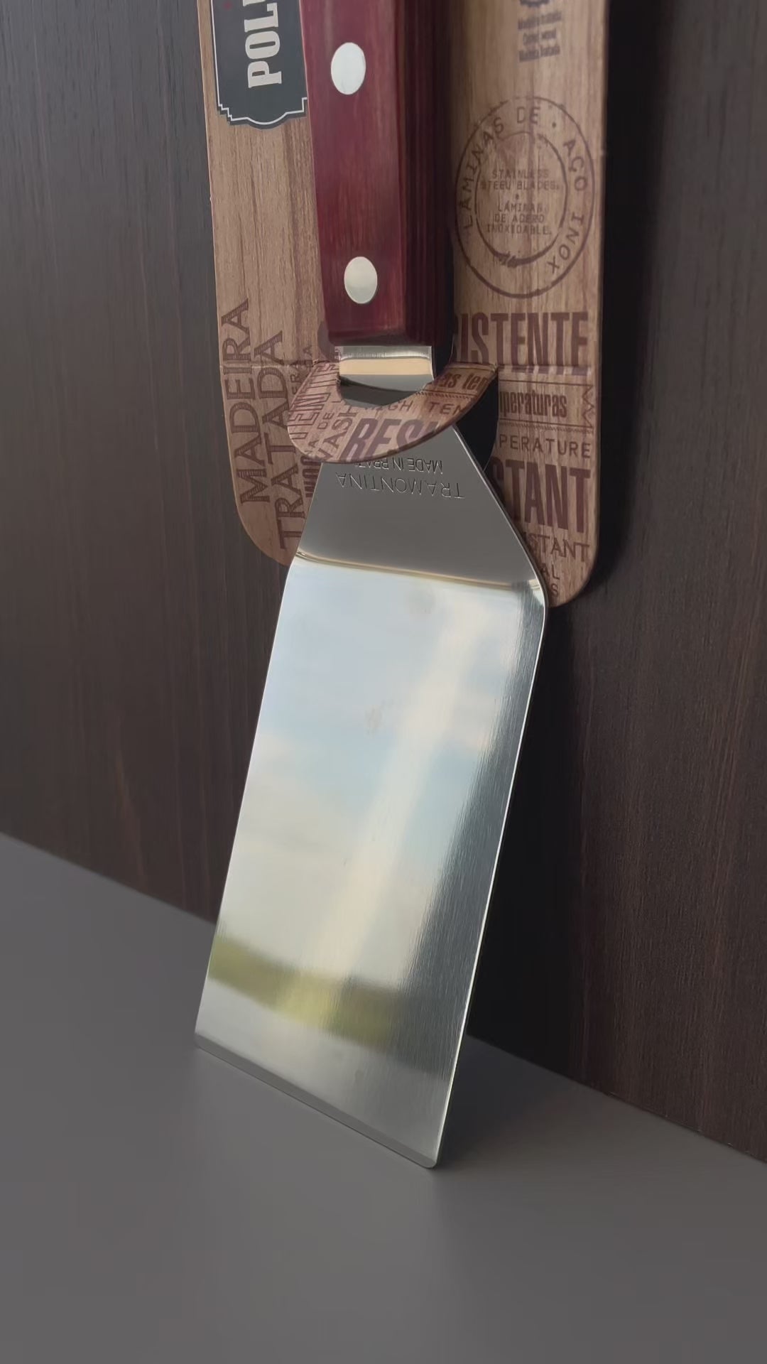 Vídeo de anúncio da espátula para fritura Tramontina, com lâmina de inox e cabo em madeira Polywood vermelho. Ideal para uso em chapas, garantindo praticidade e durabilidade. Perfeita para lanches e preparos rápidos. Encontre a espátula Tramontina na Salvador Comercial.