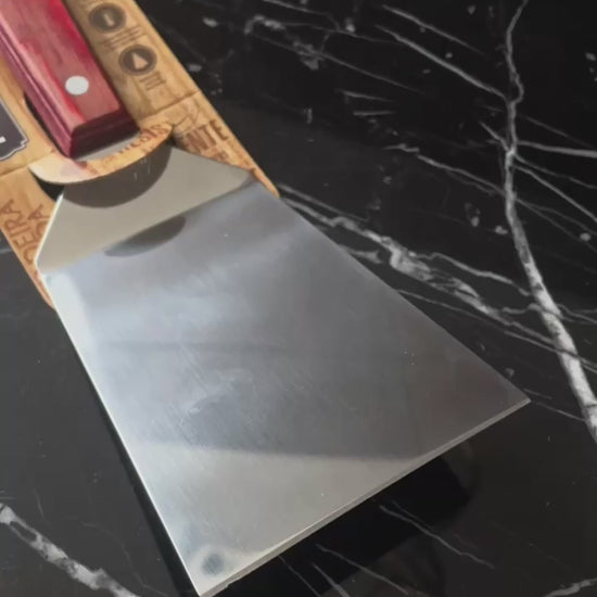 Vídeo de anúncio da espátula de fritura Tramontina, com lâmina de inox de 5 polegadas e cabo em madeira Polywood vermelho. Ideal para uso em chapas, a espátula garante praticidade e durabilidade. Encontre essa ferramenta essencial para lanches e preparos rápidos.