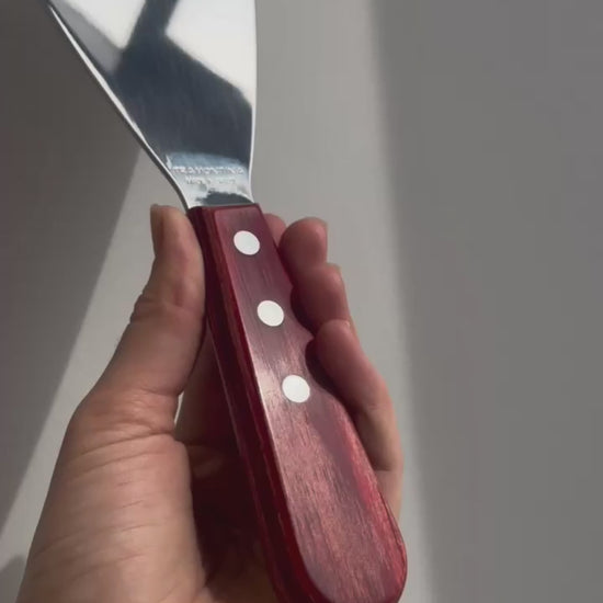 Vídeo de anúncio da espátula de fritura Tramontina, com lâmina de inox de 5 polegadas e cabo em madeira Polywood vermelho. Ideal para uso em chapas, a espátula garante praticidade e durabilidade. Encontre essa ferramenta essencial para lanches e preparos rápidos.